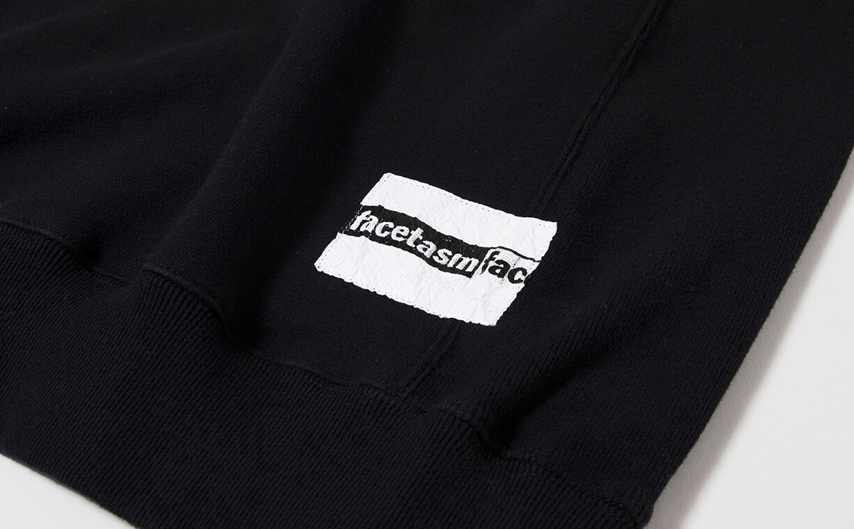 ファセッタズムのブラックのジッパー付きスウェットシャツのロゴ入りパッチのアップ